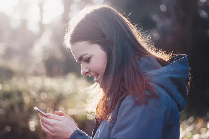 Mädchen schaut auf ihr Smartphone – das erste Handy für Kinder