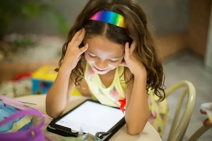Mädchen lernt lächelnd mit einem Tablet – Tablets für Kinder