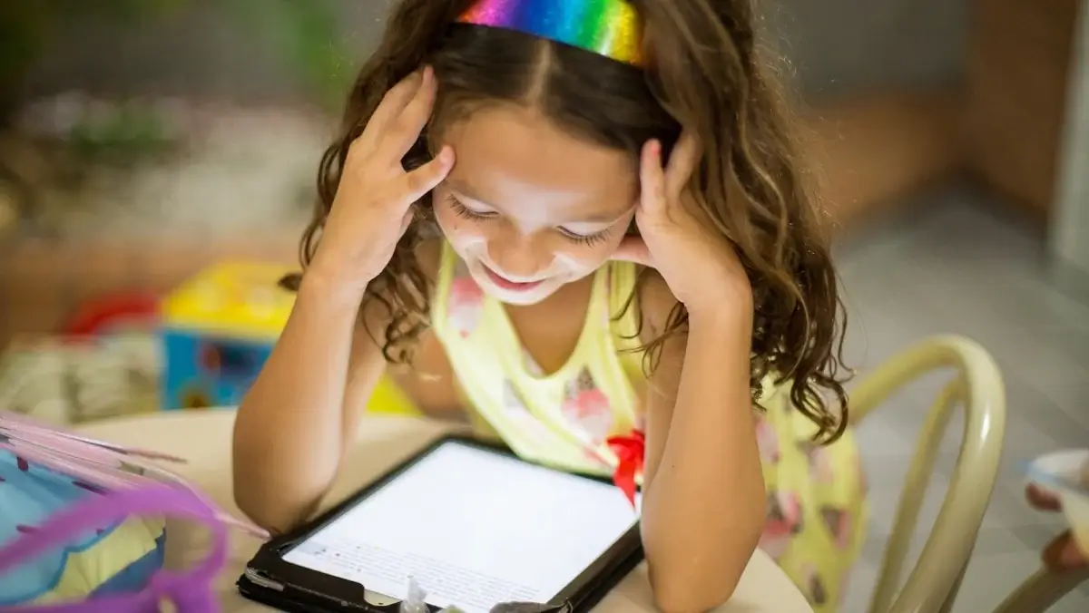 Mädchen lernt lächelnd mit einem Tablet – Technik für Kinder und Familien